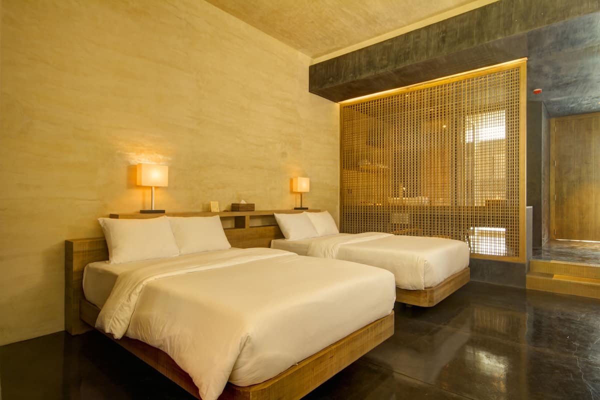 A hotel room with two beds, wooden headboards, and a large window with a view.