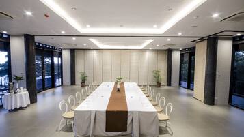 A conference room with a long table, chairs, and a central plant.
