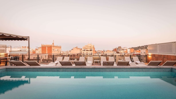 A rooftop pool with lounge chairs and a cityscape view. - Petit Palace Eixample (Barcelona)