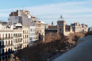 Paisagem urbana com edifícios históricos, incluindo uma torre imponente e uma roda-gigante ao fundo.
