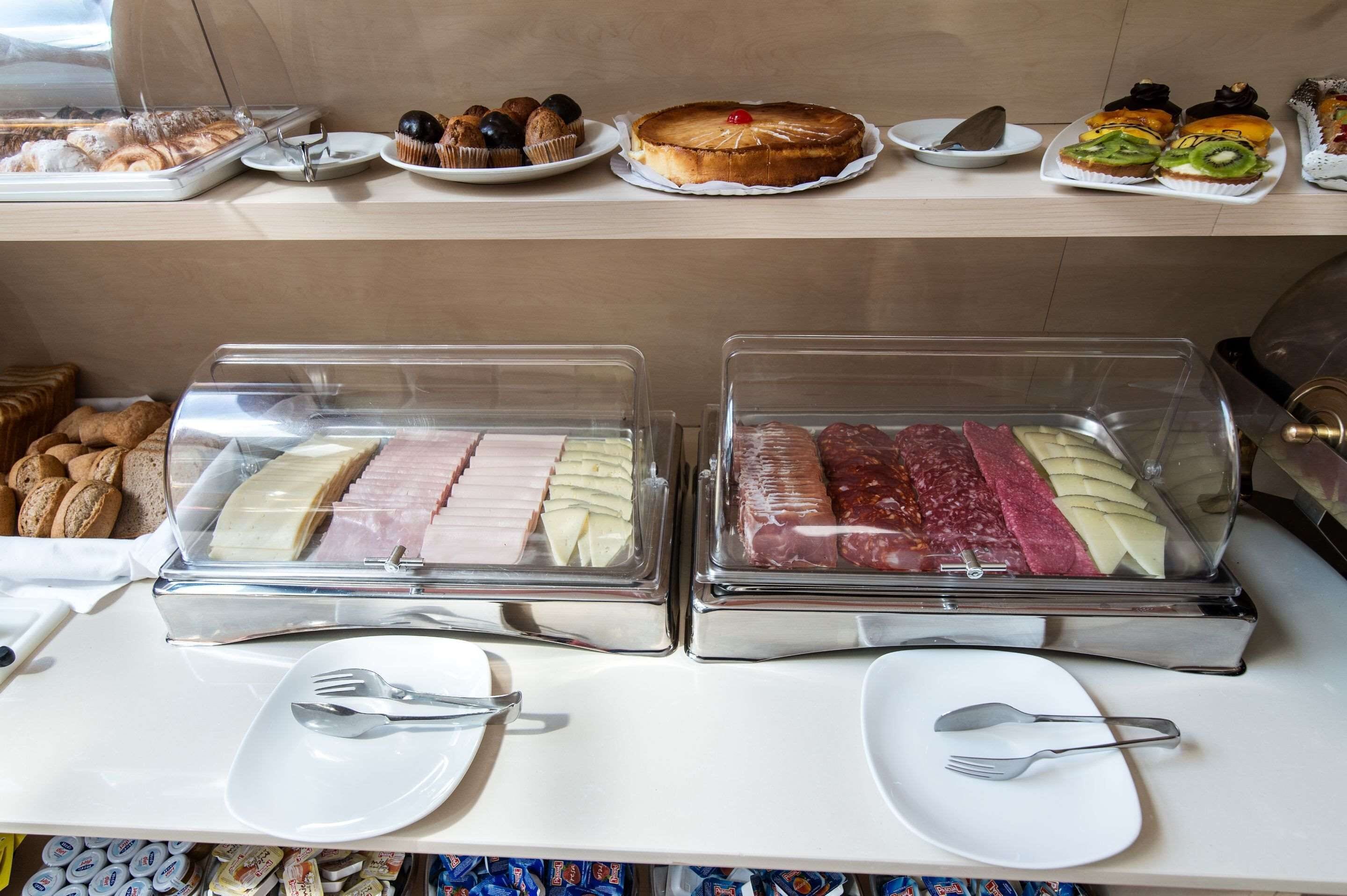 A buffet with various food items including pastries, cakes, and deli meats.