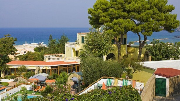 Un hotel frente al mar con piscina, zona de estar exterior y vistas al océano.
