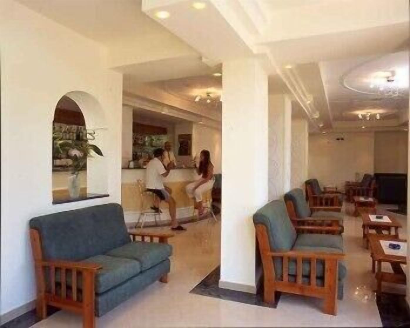 A hotel lobby with a bar area, seating arrangements, and a large mirror.