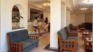 Vestíbulo de hotel con zona de bar, asientos y un espejo grande.