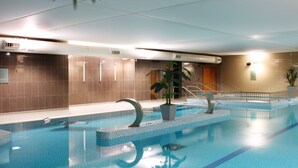 Ein Innenpool mit klarem, blauem Wasser, gefliesten Wänden und einer Zimmerpflanze.
