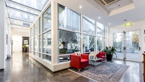 A spacious lobby with large glass windows, a red sofa, and a patterned rug. - Hotel Carpi (Carpi)
