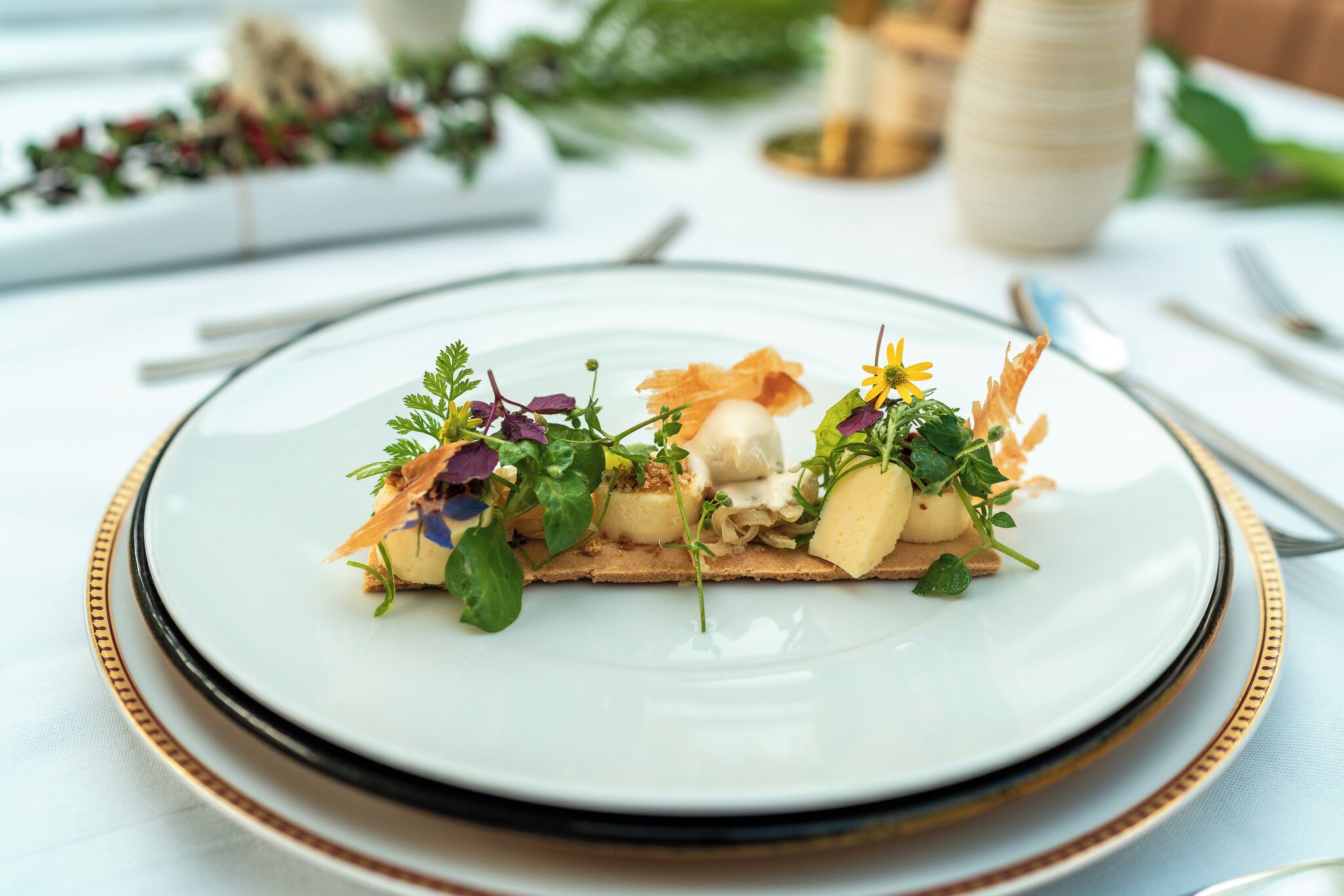 A plate of food with various garnishes and a white plate with a gold rim.