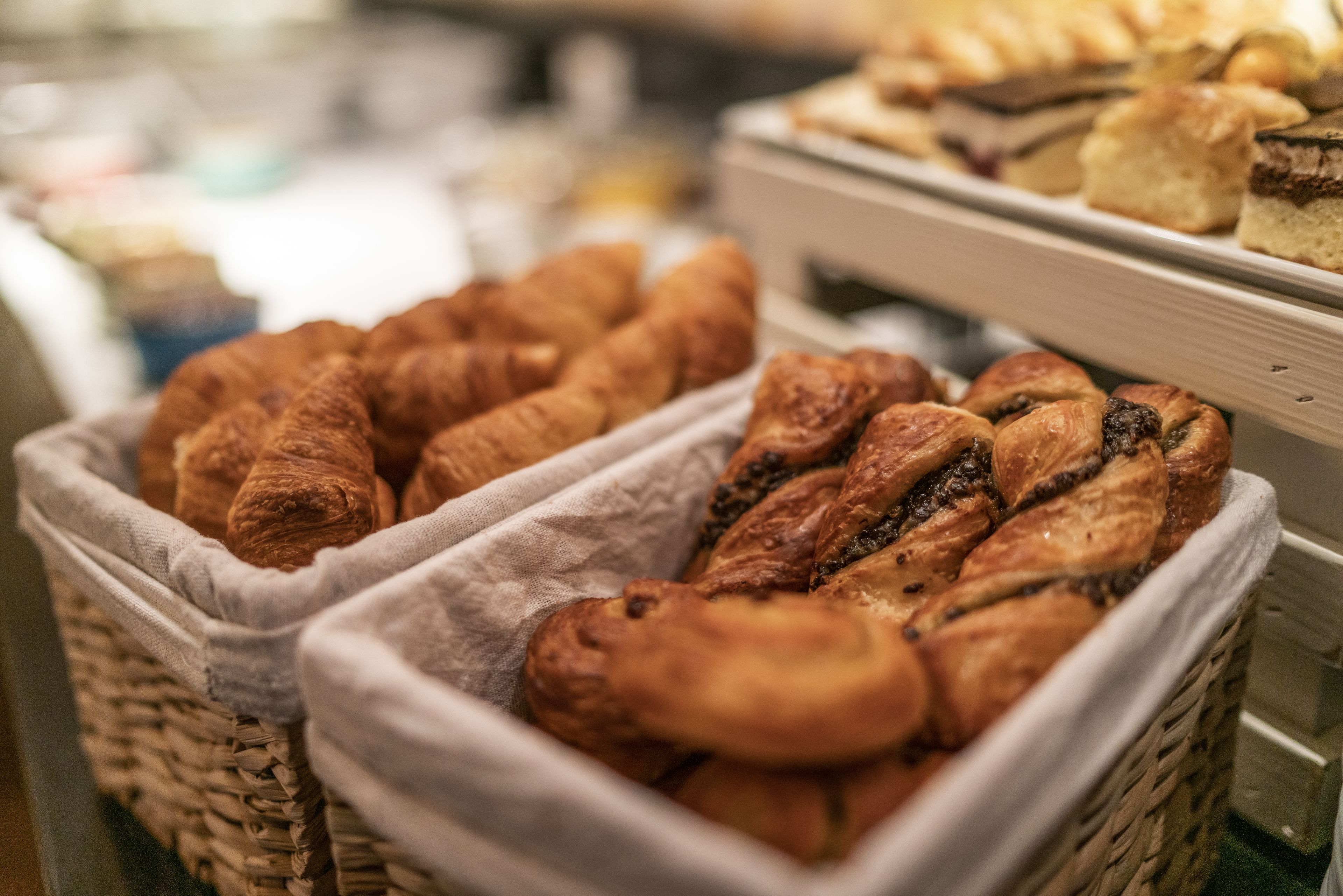A bakery display with various baked goods, including croissants and pastries, arranged in wicker baskets.