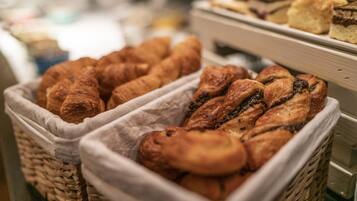 A bakery display with various baked goods, including croissants and pastries, arranged in wicker baskets.