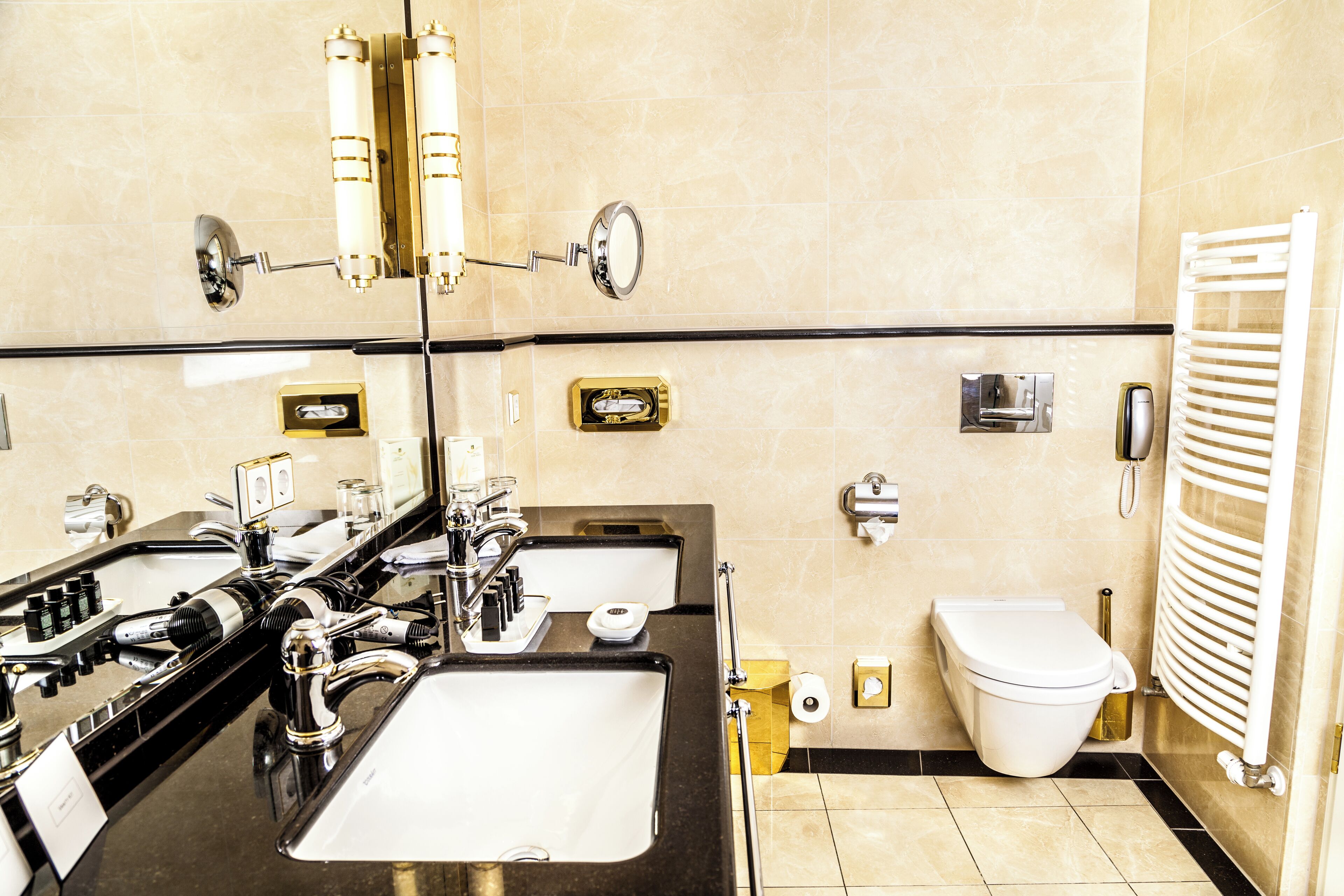 A modern bathroom with a large mirror, dual sinks, a toilet, and a towel rack.