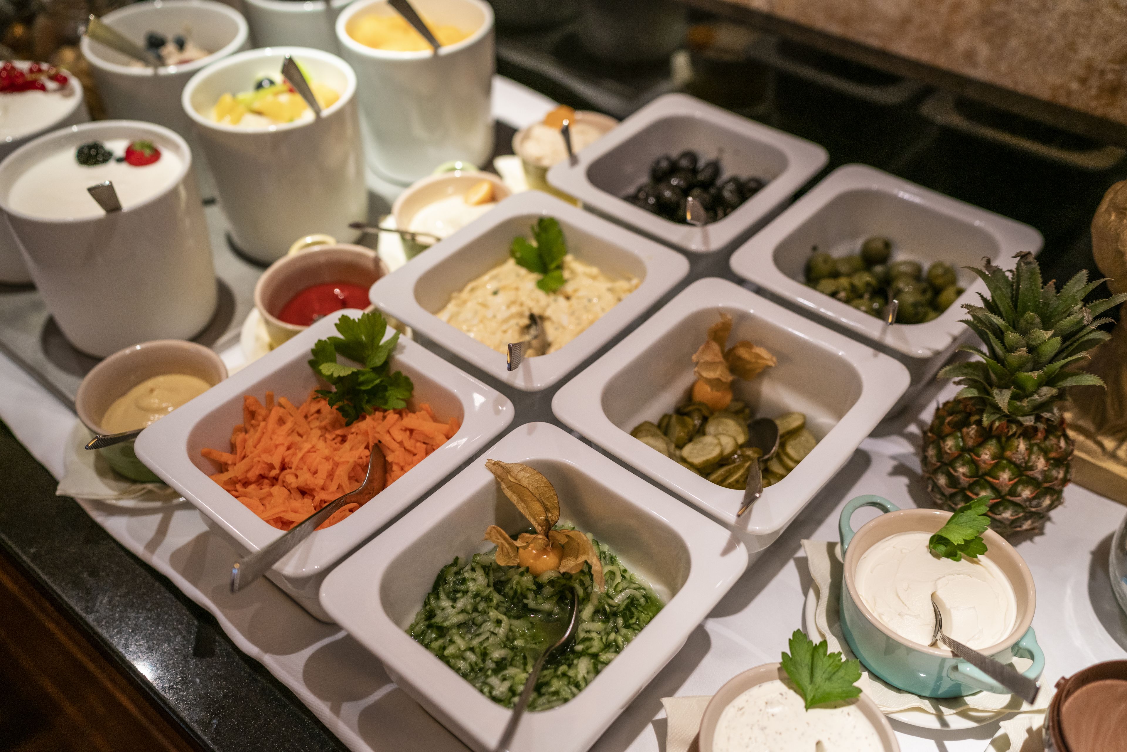 Een buffet met diverse etenswaren, zoals salades, dips en fruit.