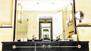 A bathroom with a large mirror, black countertop, and gold fixtures.