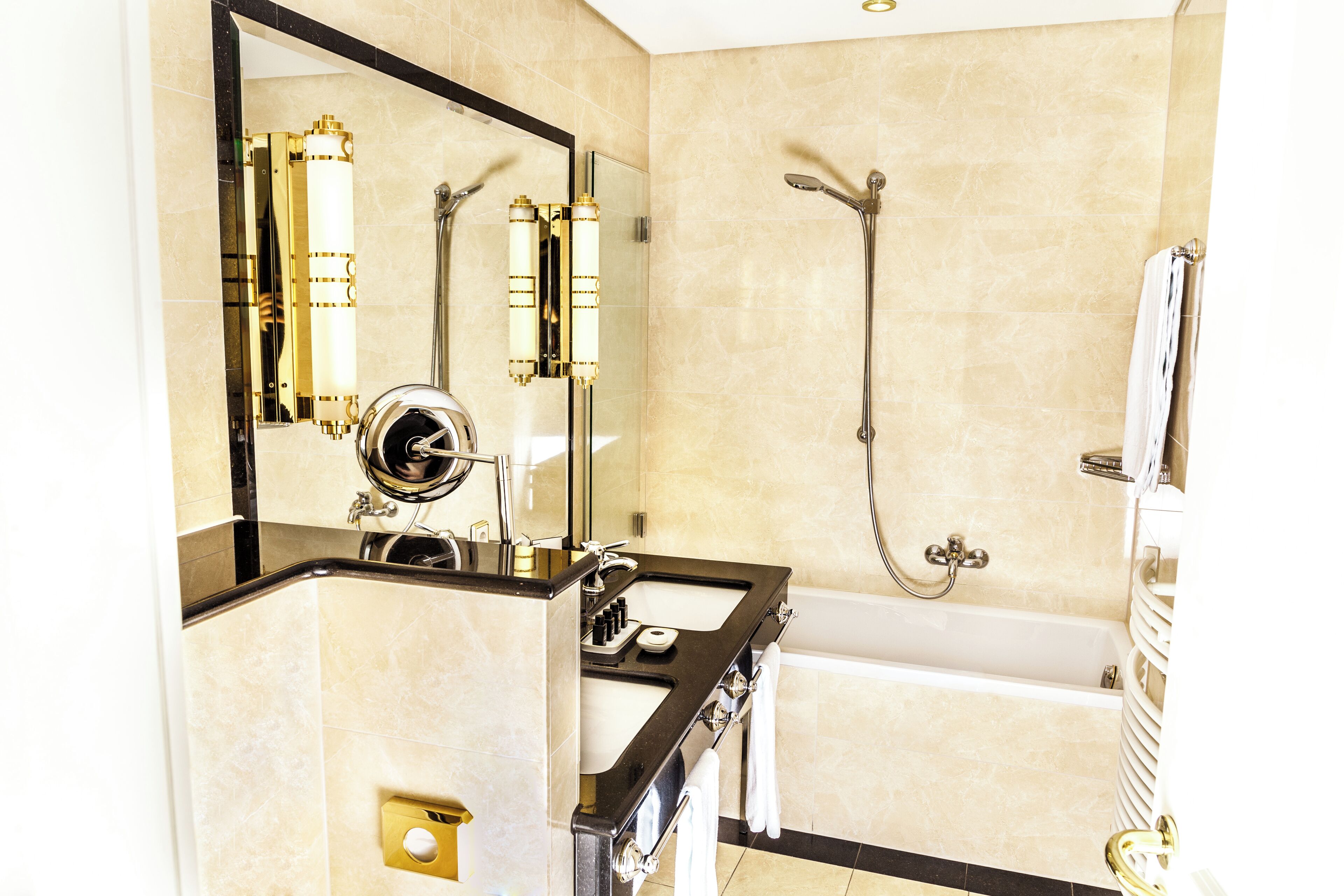 A modern bathroom with a black countertop, a large mirror, a bathtub, and a shower.