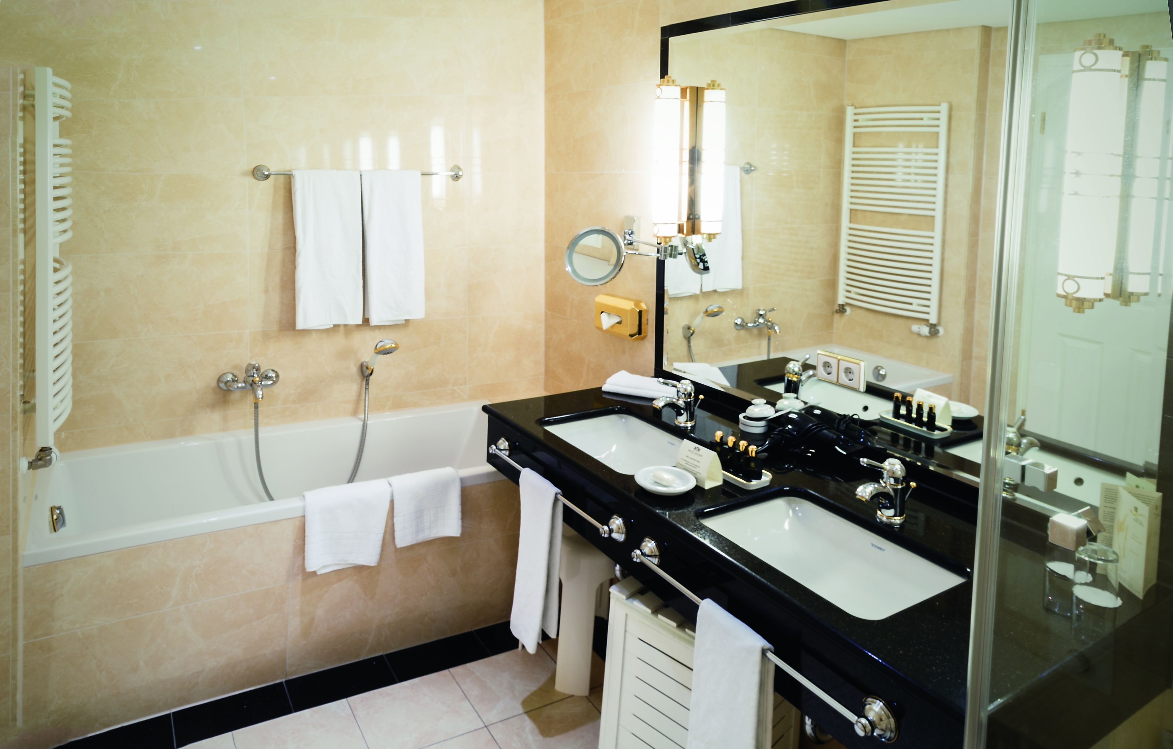 A bathroom with a bathtub, two sinks, a mirror, and a towel rack.
