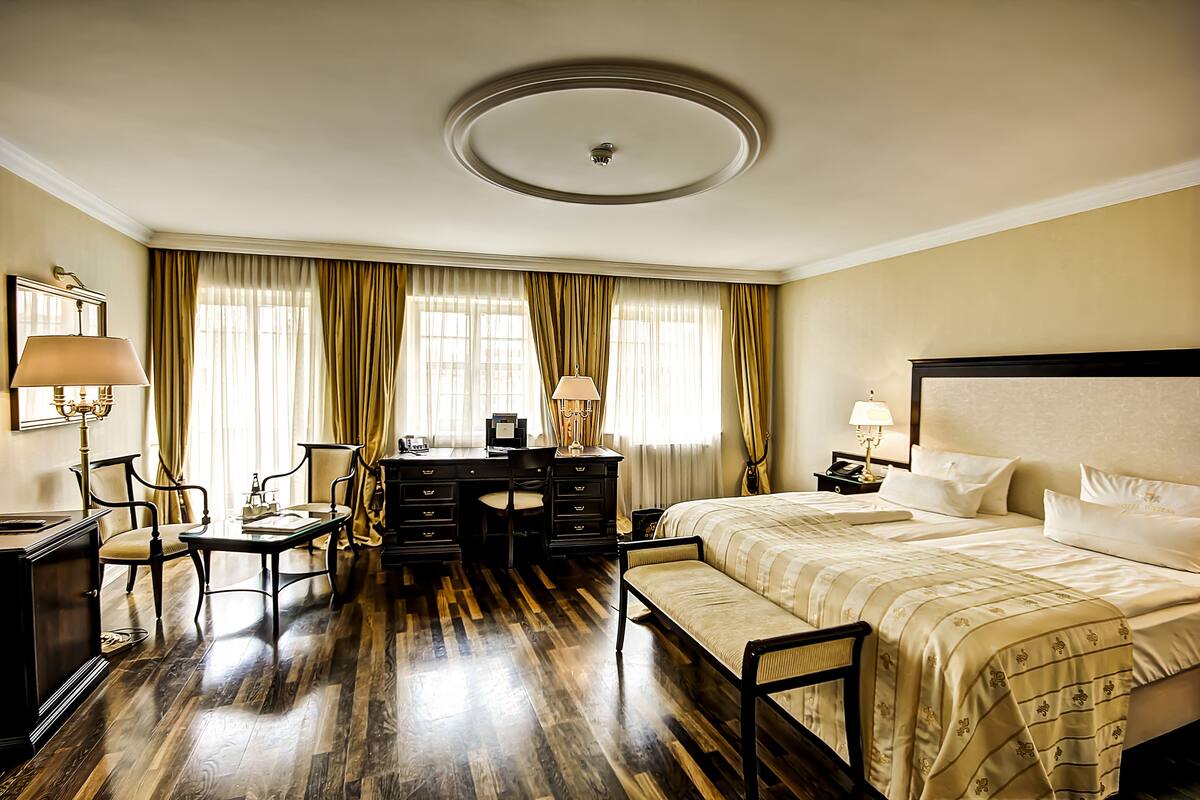 A hotel room with a bed, desk, chairs, and a dresser.