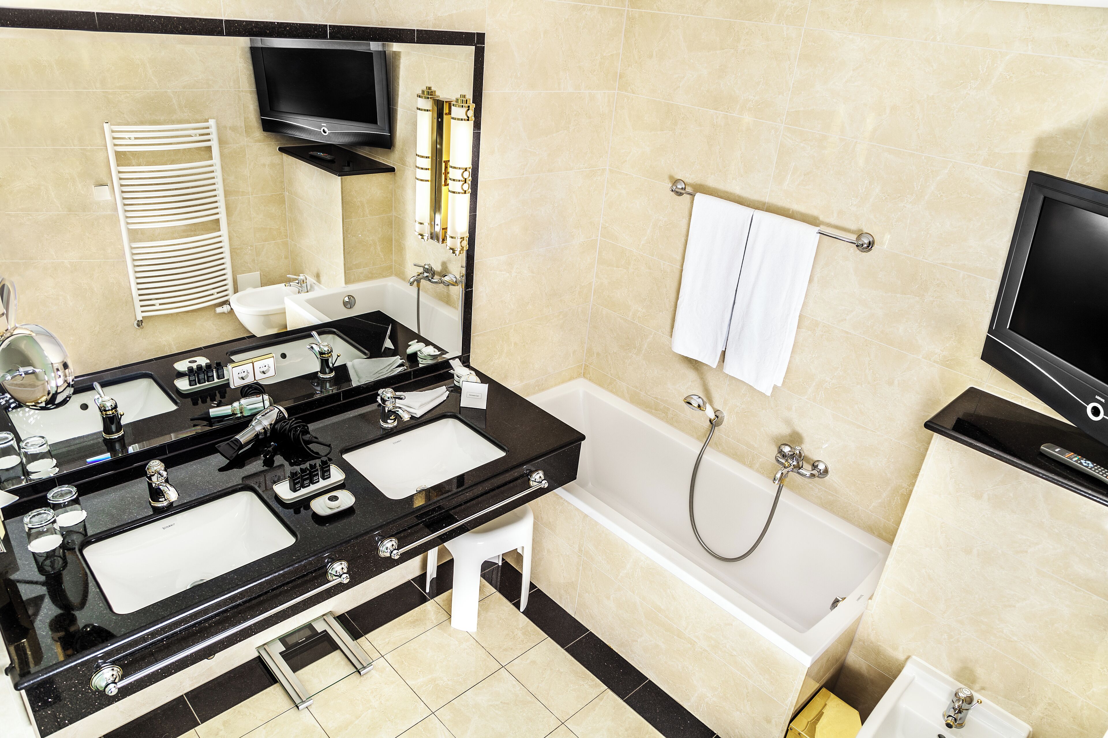 Une salle de bain moderne avec un lavabo noir, une baignoire blanche et un grand miroir.
