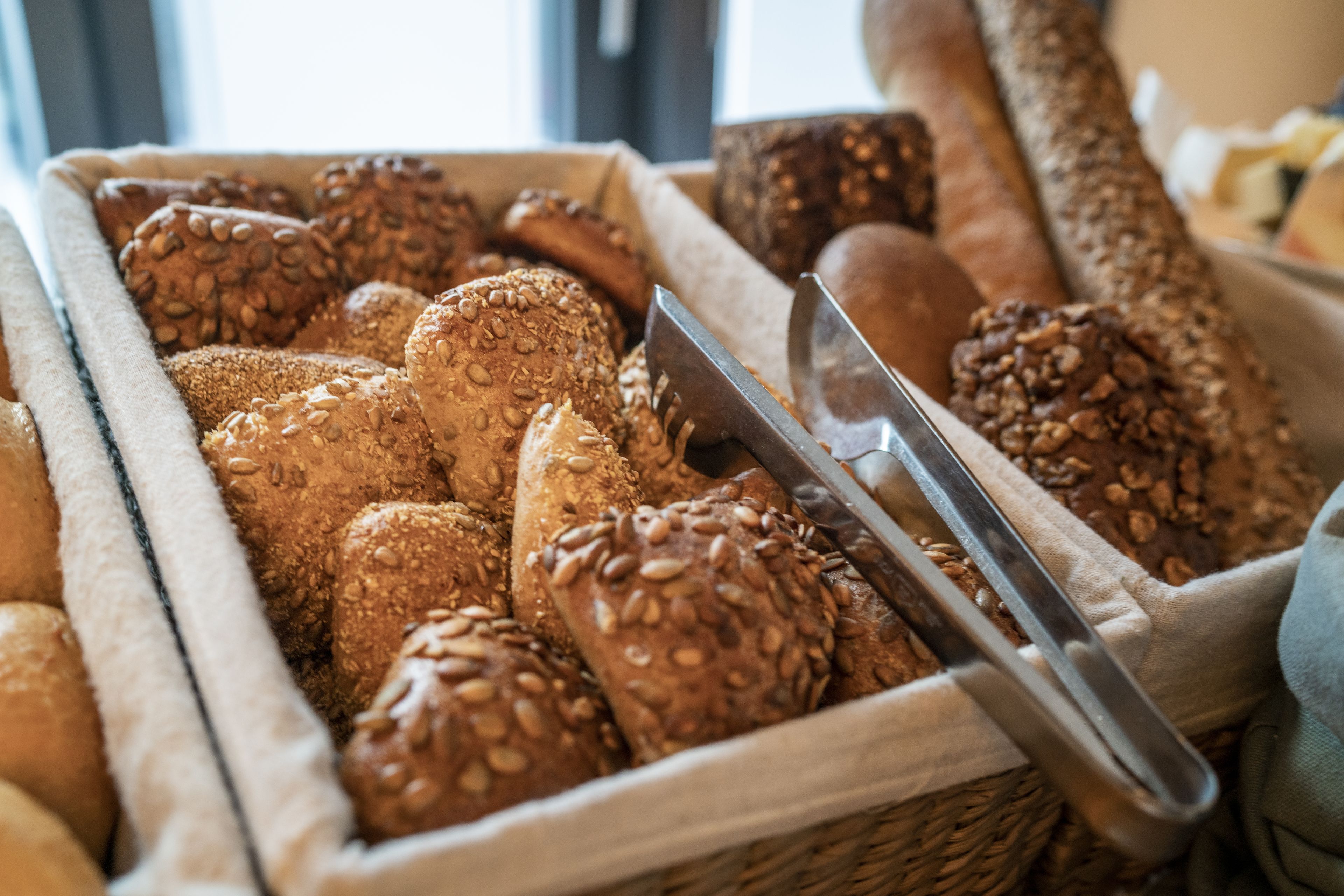 A variety of breads in a basket, including some with seeds.