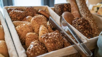 A variety of breads in a basket, including some with seeds.