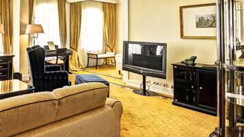 A hotel room with a sofa, a television, a desk, and a chair.