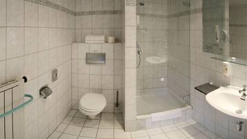 A modern bathroom with a glass-enclosed shower, a toilet, and a sink.