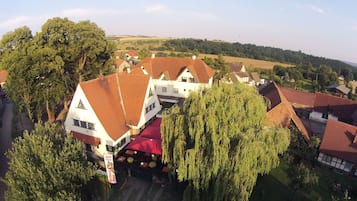 A traditional European-style building with a red-tiled roof, surrounded by lush greenery and a rural landscape.
