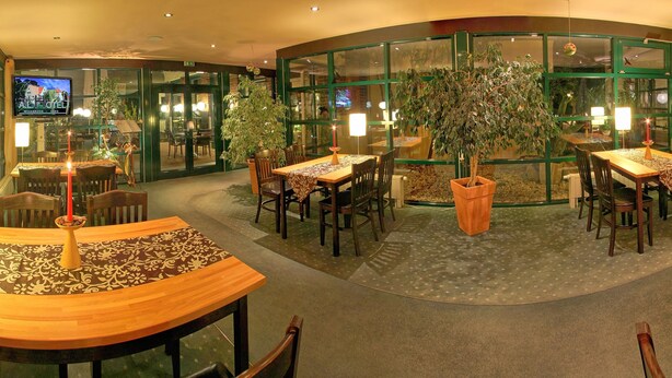A hotel lobby with a central seating area, multiple tables, chairs, and potted plants. - Hotel & Restaurant 5 Linden (Südharz)