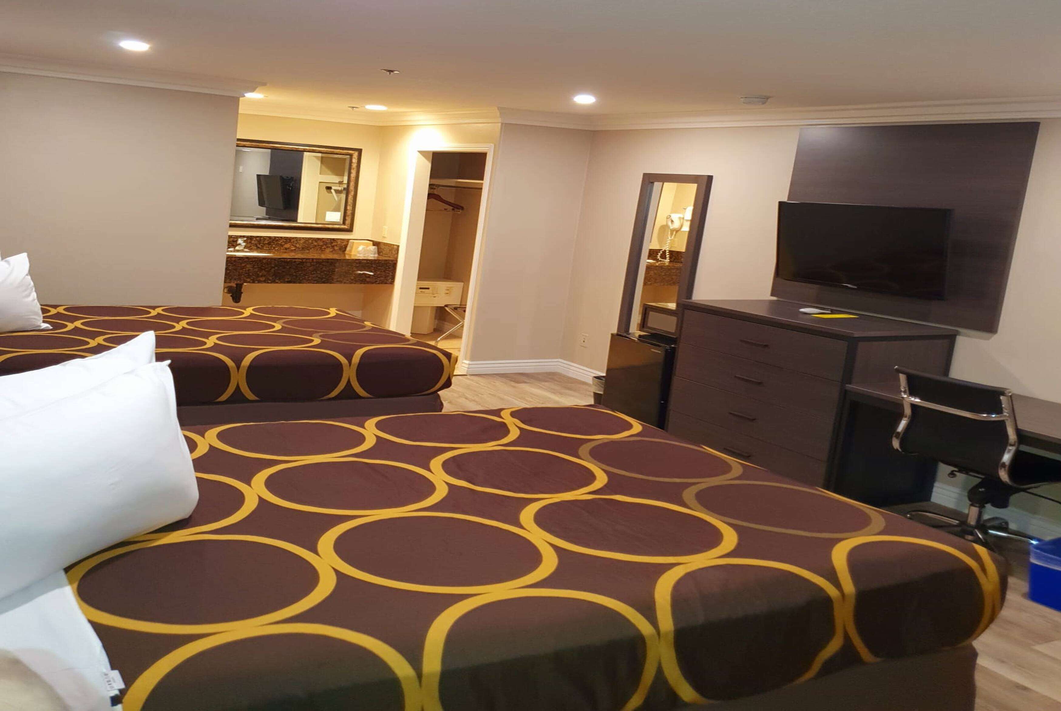 Ein Hotelzimmer mit zwei Betten, einem Fernseher, einem Schreibtisch und einem begehbaren Kleiderschrank.