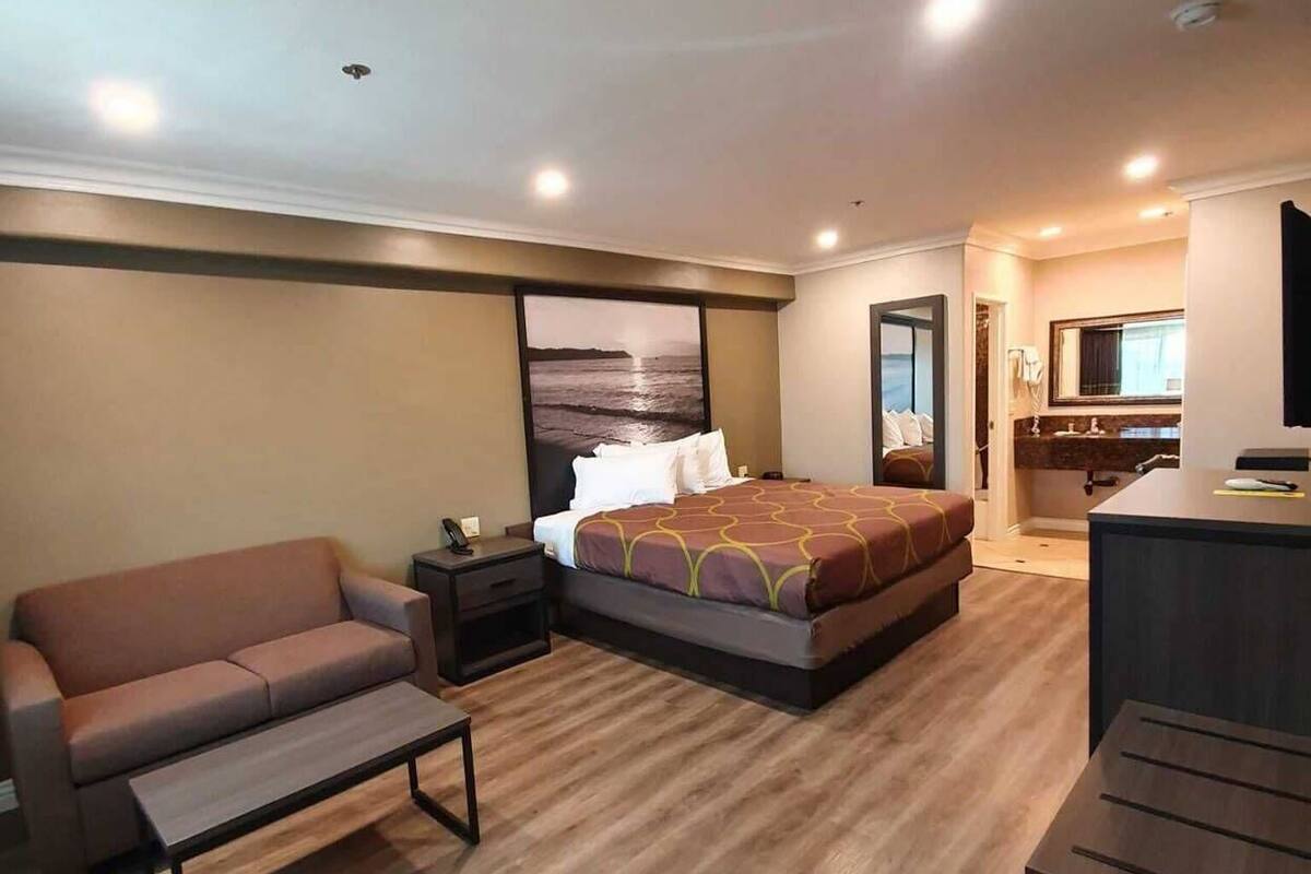 A hotel room with a bed, a sofa, a desk, and a small table.