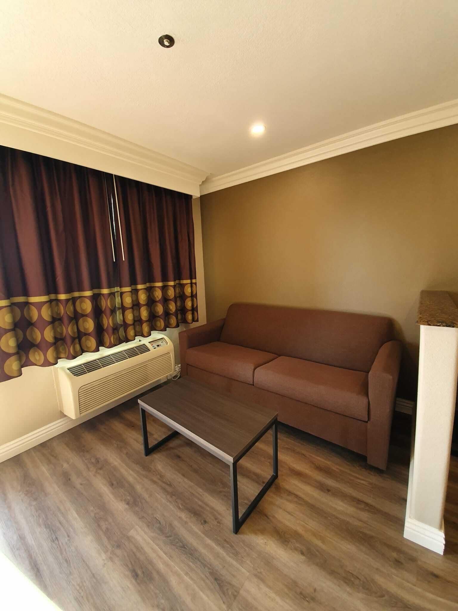 A living room with a brown sofa, a wooden coffee table, and a wall-mounted air conditioner.