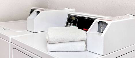 A laundry area with two front-loading washing machines and a folded white towel on the counter.