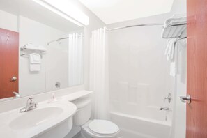 Bathroom features a white sink, toilet, and bathtub with a shower curtain, along with a large mirror and towel rack.