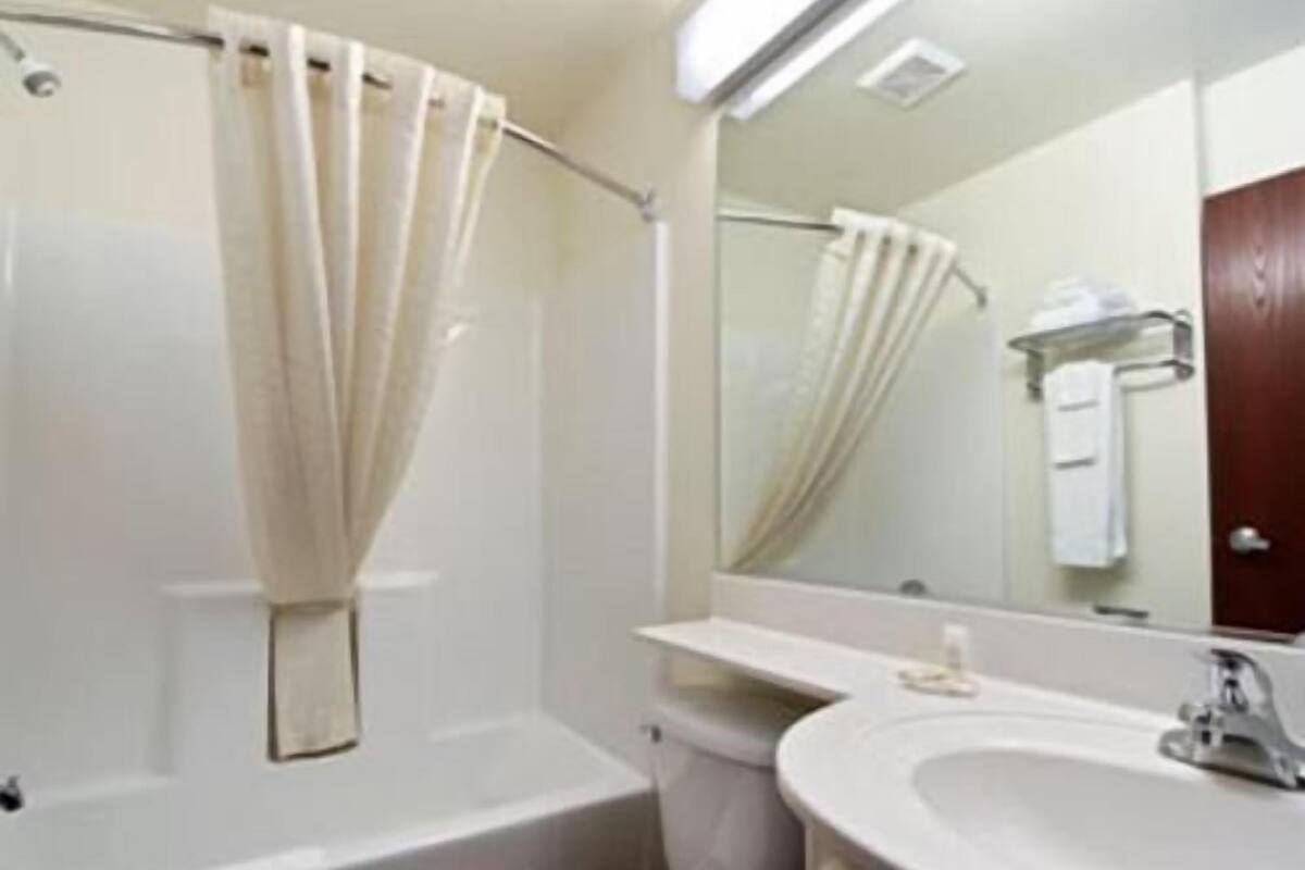 A bathroom with a bathtub, toilet, sink, and a mirror.