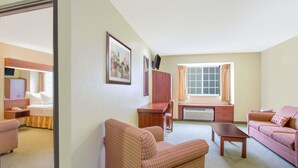 Una camera d'hotel con un letto, una scrivania, una sedia, un divano e un televisore.