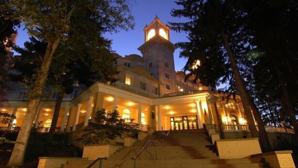 Un hotel imponente con una torre caratteristica, diverse scale e un ingresso ben illuminato.