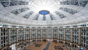 Un ampio atrio a più livelli con un'area circolare centrale, circondato da numerosi piani di camere con balconi.