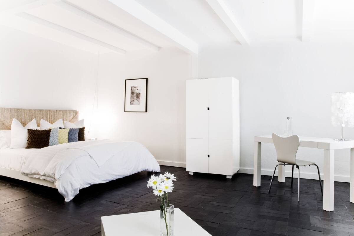 Une chambre à coucher moderne et minimaliste, comprenant un lit, une table de chevet et un bureau avec une chaise.