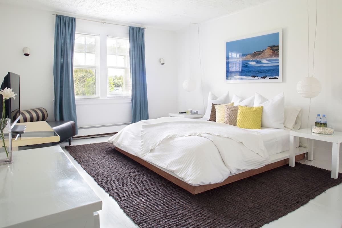 Une chambre à coucher moderne avec un grand lit, une table de chevet, un bureau et une chaise.