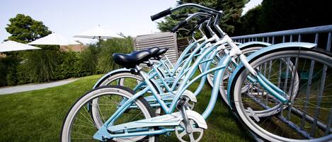 A row of light blue bicycles parked on a grassy lawn.