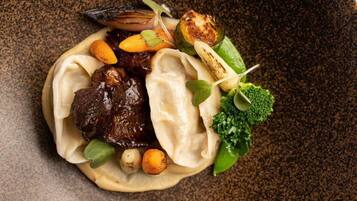A dish with dumplings, meat, vegetables, and a garnish.