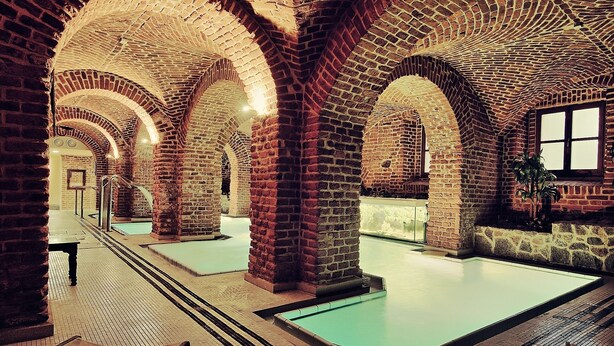 Zona de piscina con arcos de ladrillo y una piscina cristalina.