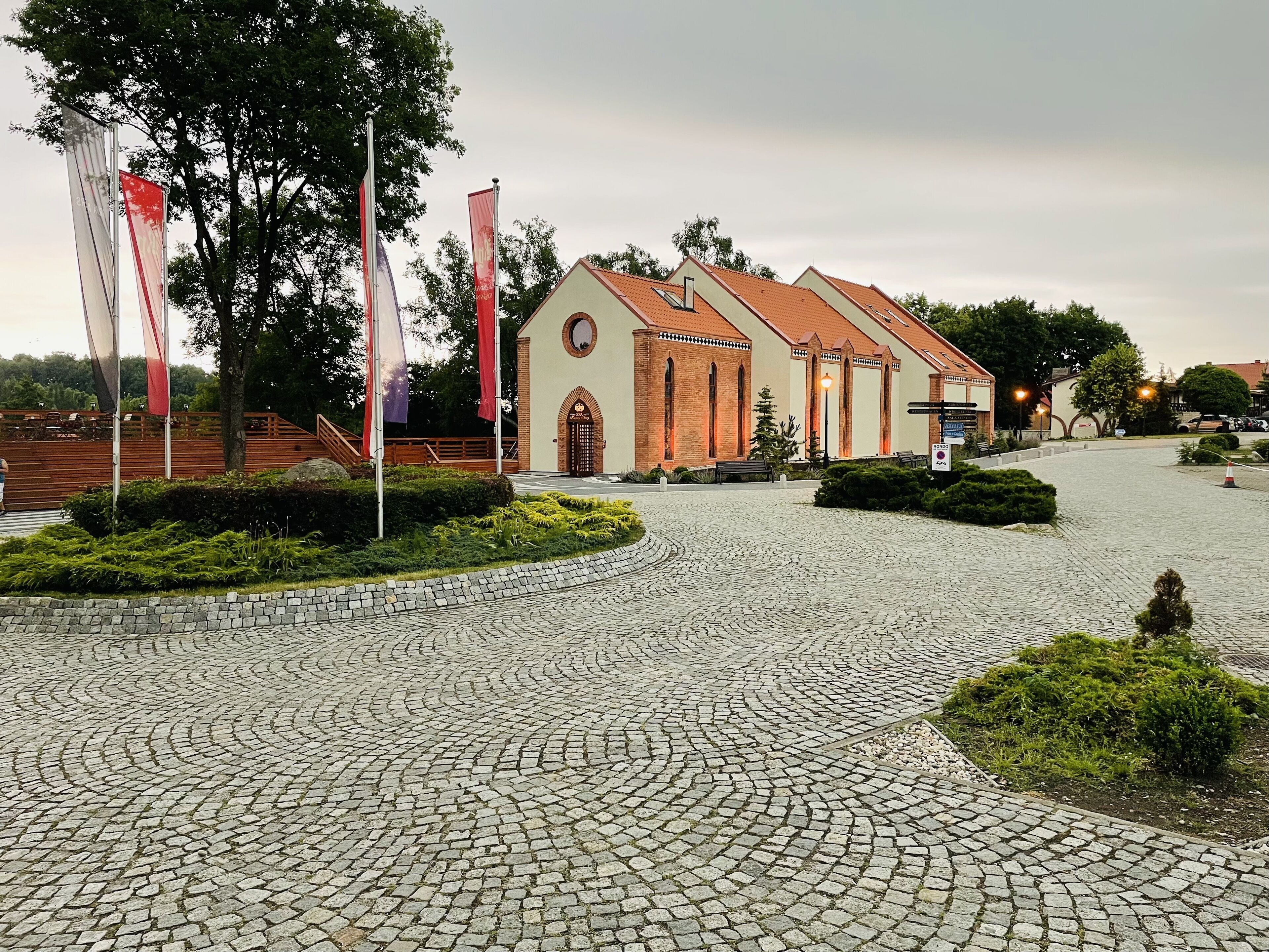 Une cour pavée de pierres, avec une église dotée d’un toit en tuiles et de fenêtres en arc de cercle.