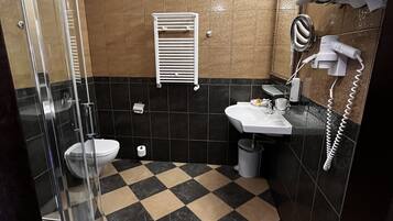 A bathroom with a checkered floor, a toilet, a sink, a towel rack, and a hairdryer.