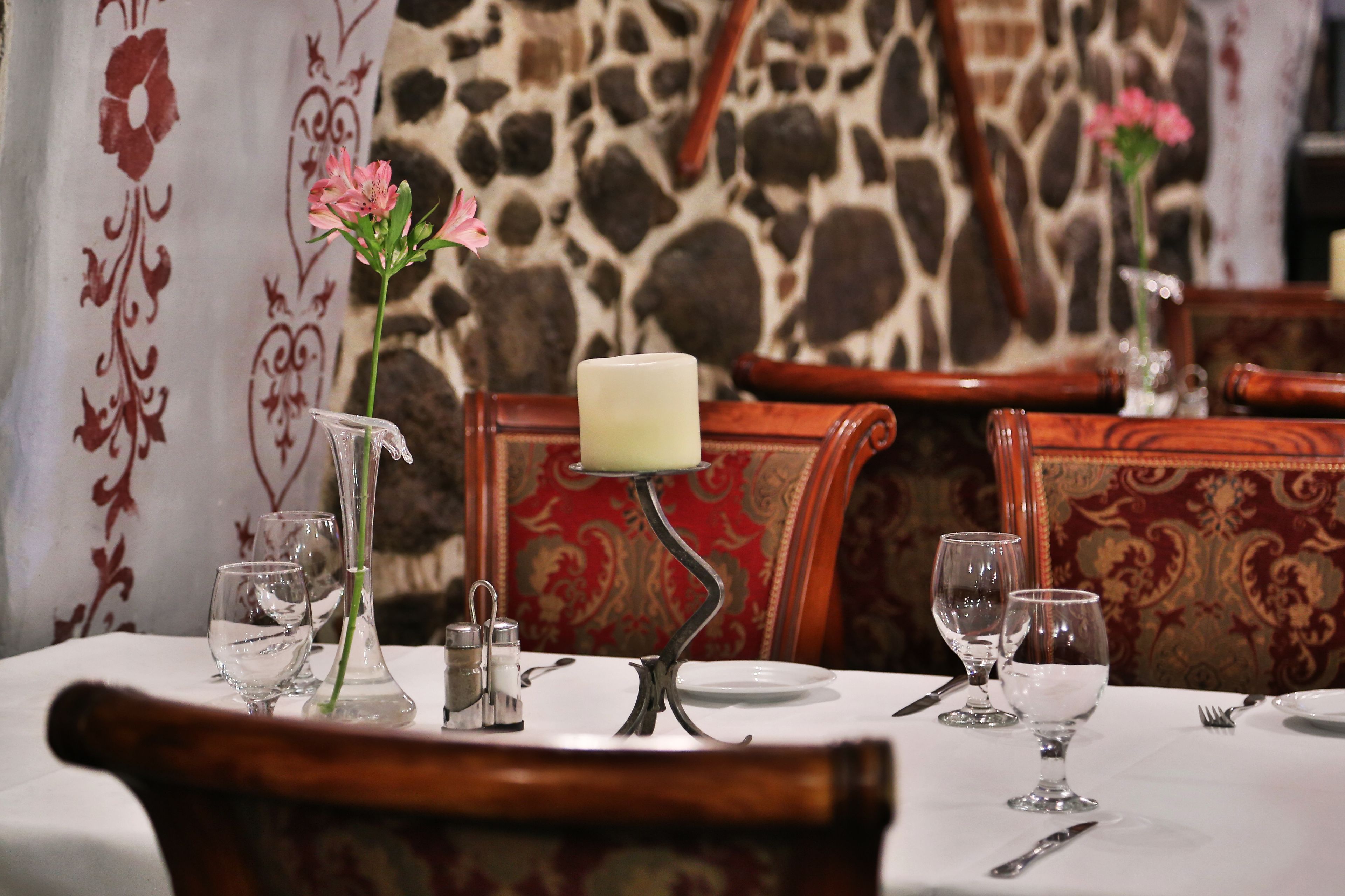 A dining table set with a candle, salt and pepper shakers, and a vase with flowers.