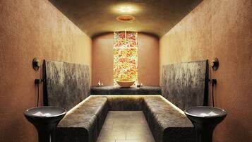 Une salle de bain moderne avec deux lavabos, un mur décoratif central et un plafond à texture.