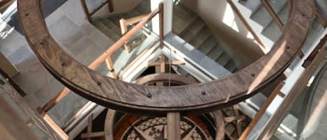 Eine Wendeltreppe mit hölzernen Geländern und einem runden farbenfrohen Glasfenster oben.
