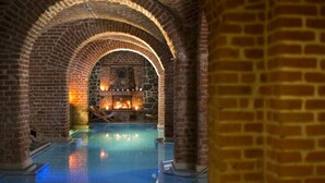 Una piscina interior con arcos de ladrillo y una chimenea de piedra.