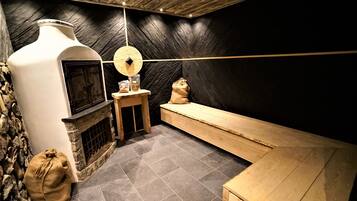 A rustic interior with a stone fireplace, a wooden bench, and a stone wall.