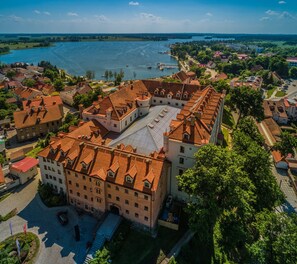 An aerial view of a historic building complex with a central courtyard, surrounded by residential buildings and a river.