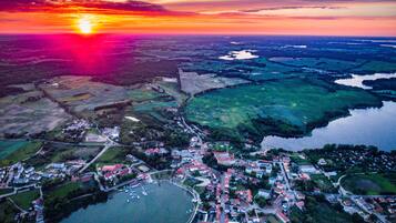 An aerial view of a town with a lake, surrounded by fields and a sunset in the background.