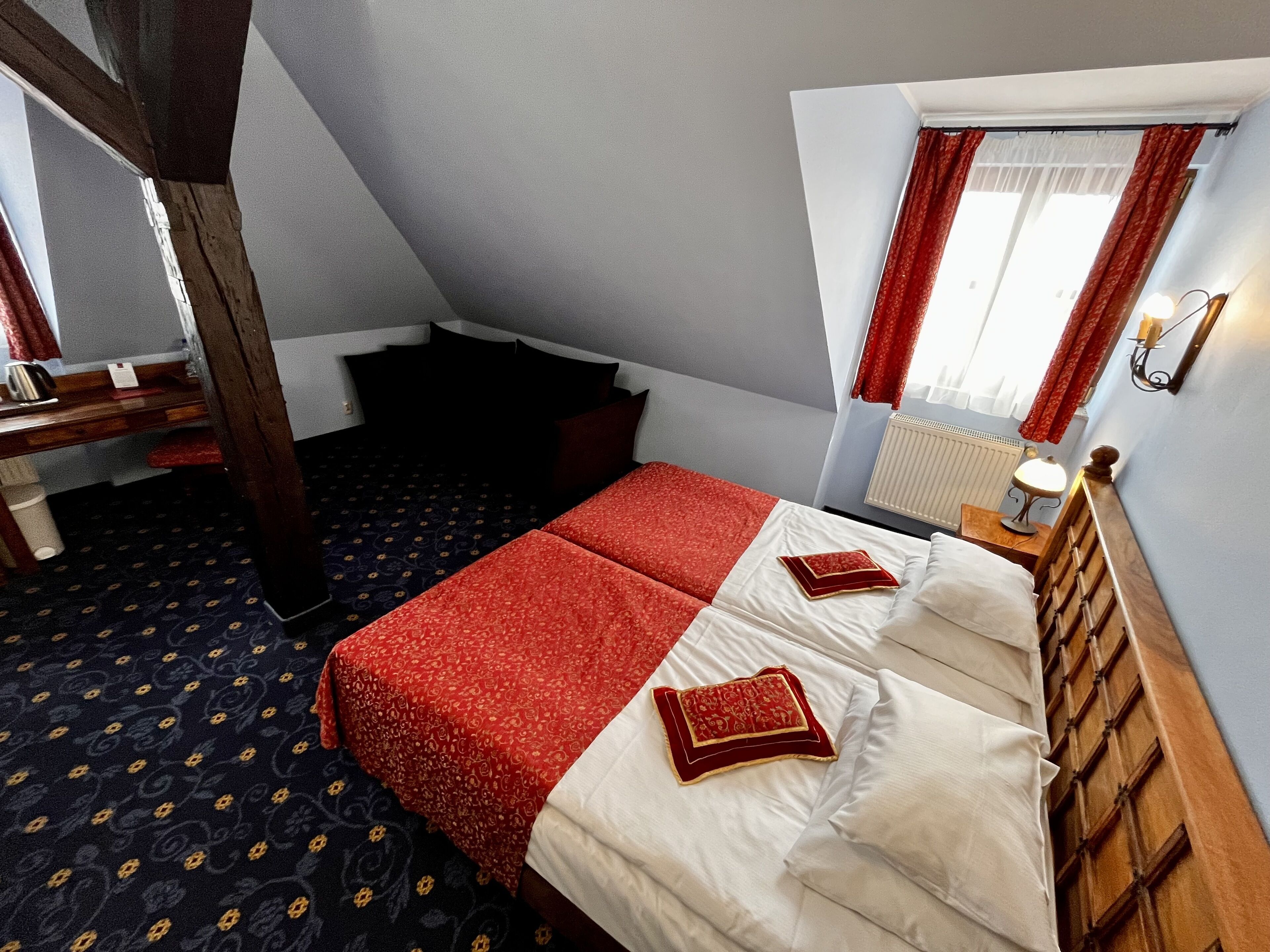 Une chambre à coucher avec un lit, une table de chevet, une lampe et une fenêtre avec des rideaux.
